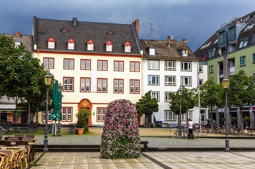 A European street with colorful buildings, a flower-covered statue, and bicycles. 3