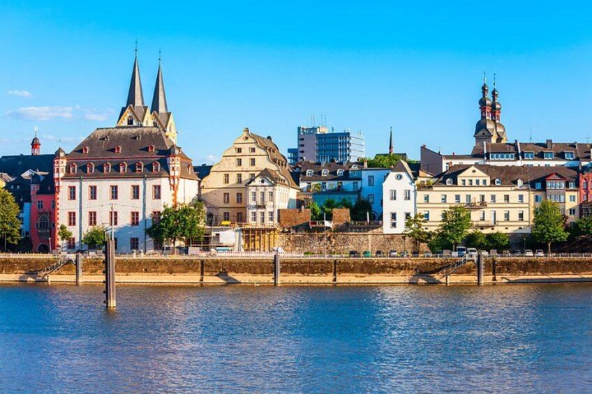 A river with buildings along the banks, including a church with two spires and a bridge in the foreground. 1