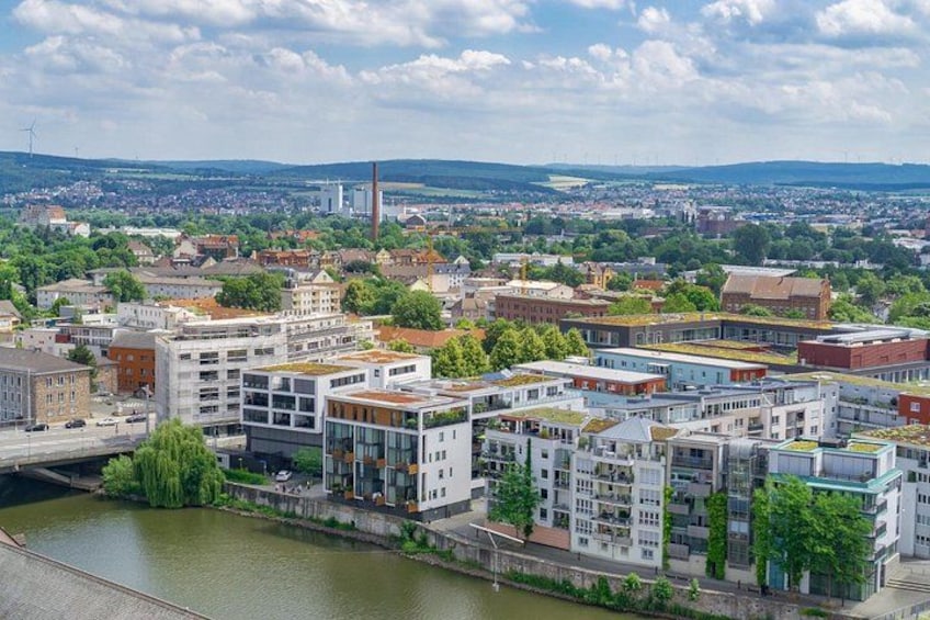 En flod med bygninger langs bredden, en bro og en fjerntliggende industriskærsæt. 5