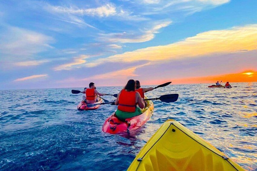 Personas haciendo kayak en un cuerpo de agua durante el atardecer. 4