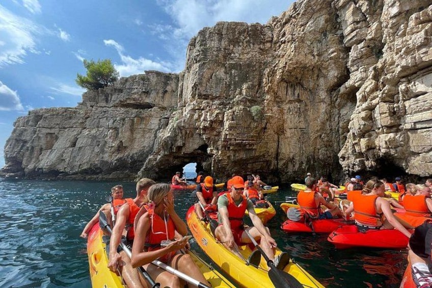 Personas en kayaks amarillos y rojos sobre un cuerpo de agua, con acantilados rocosos al fondo. 2