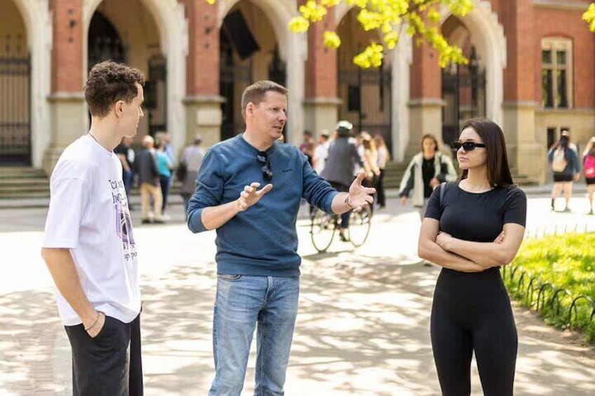 Three people conversing outdoors in a courtyard with a building in the background. 1
