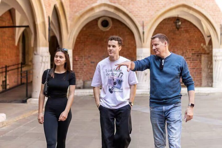 Three people walking in an outdoor area with brick arches. 3
