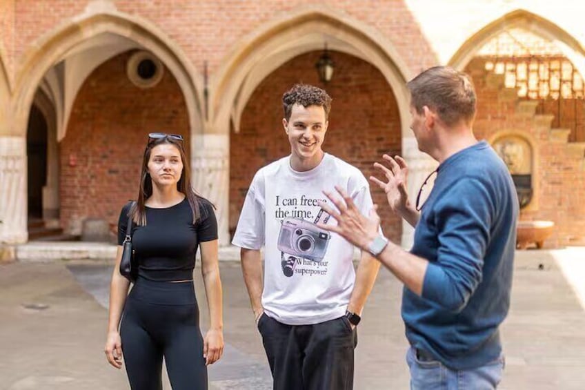 Three people standing in an outdoor area with brick arches in the background. 5