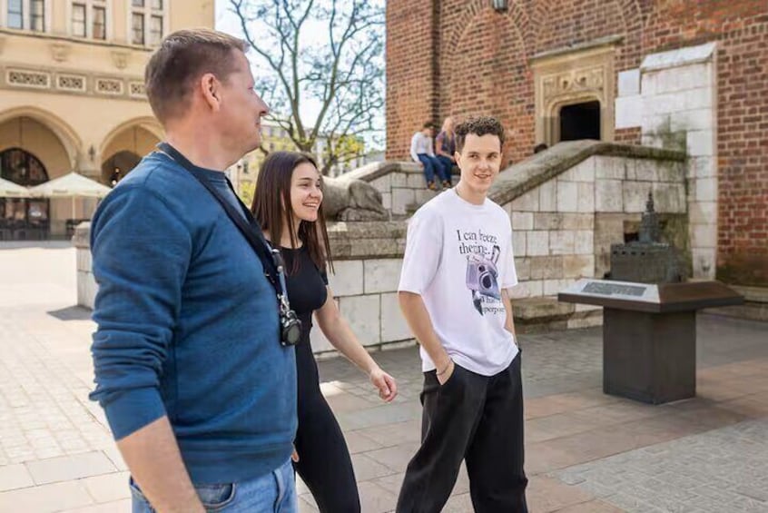 Three people standing outdoors near a historic building with arches and stone steps. 2