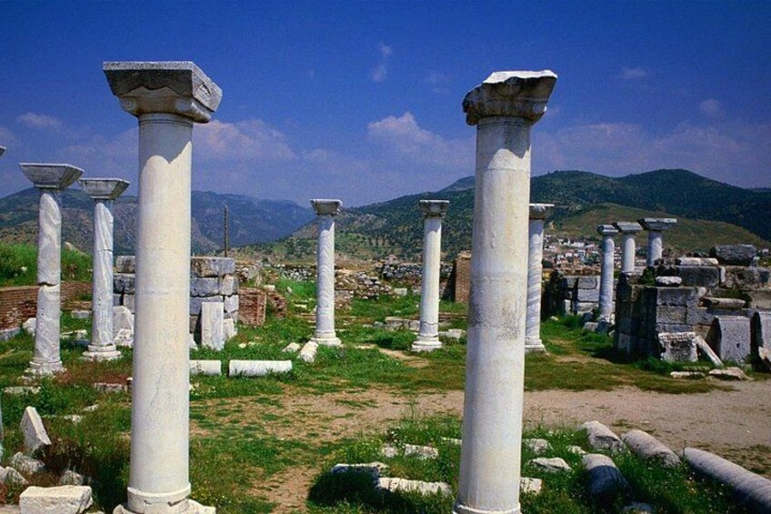 Anciennes colonnes de pierre blanche, dans un état de ruine, avec une chaîne de montagnes en arrière-plan. 2