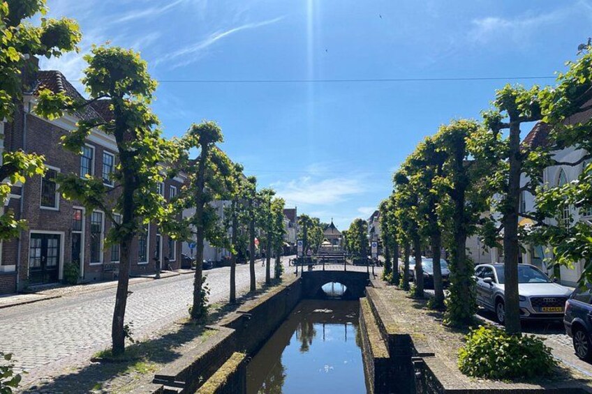 A canal with a bridge, lined with trees and buildings. 4