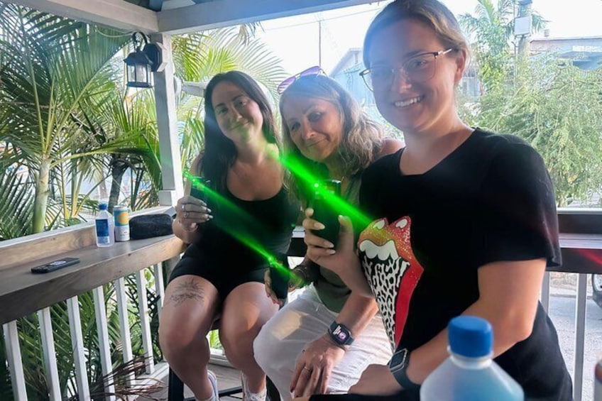 Three people sitting on a porch with a tropical background. 5