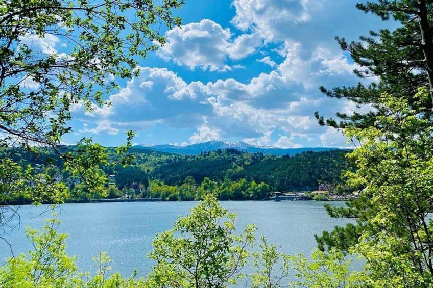 A lake surrounded by trees and mountains under a blue sky. 2
