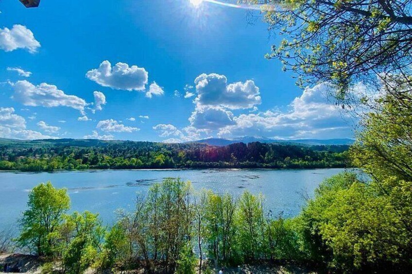 A lake surrounded by trees and hills under a clear sky. 4