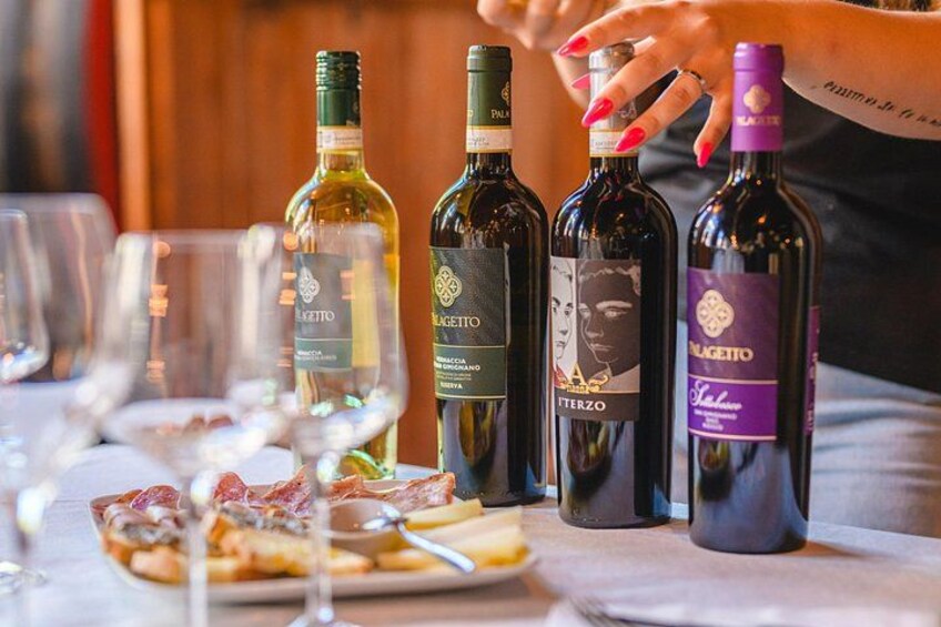 A table with wine bottles and glasses, and a plate of food. 1