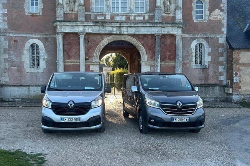 Two parked cars in front of a historic building with an arched entrance. 4