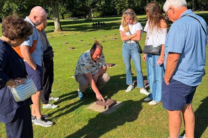 A group of people in a park with a person kneeling on the grass, possibly working on something. 3