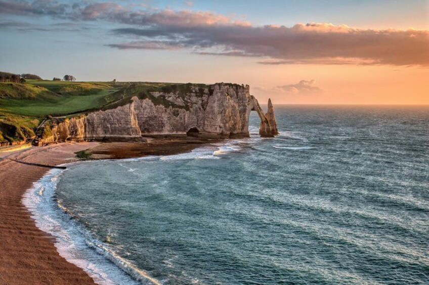 A coastal landscape with a prominent chalk cliff formation and a beach. 3