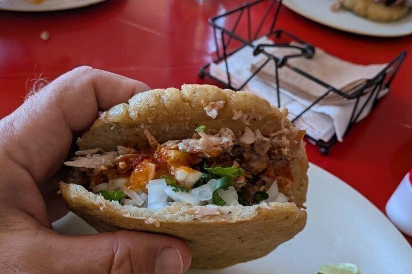Una mano sostiene un burrito a medio comer, con ingredientes visibles como carne, cebolla y salsa. 2