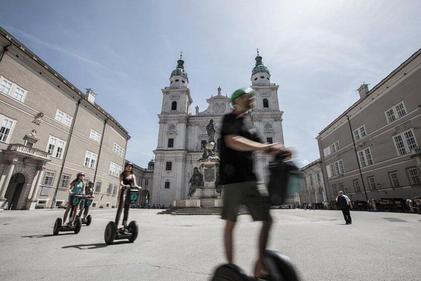 A historical building with two towers, a person on a segway, and another person on a bicycle. 4