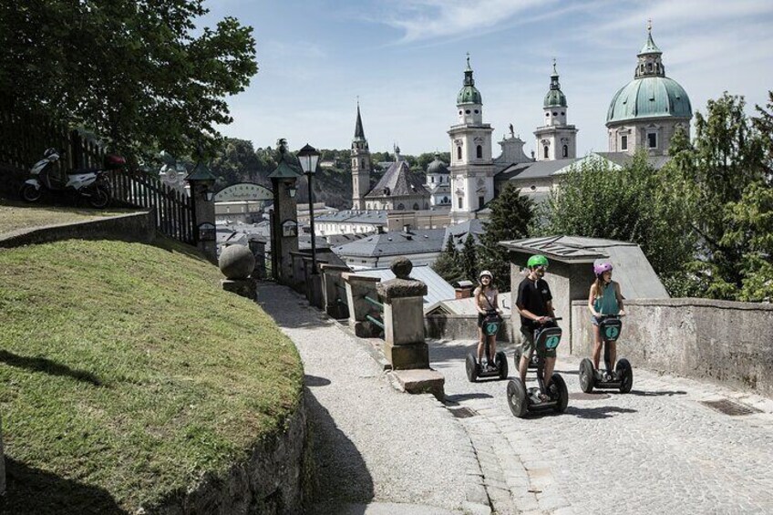 People riding segways on a cobblestone path with a historic building in the background. 1