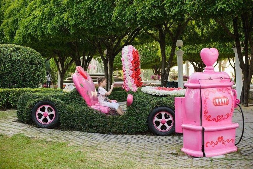 A girl in a car at the Dream World amusement park in Bangkok. Bushes and lawn, decorations for Valentine's Day, Valentine's Day 3