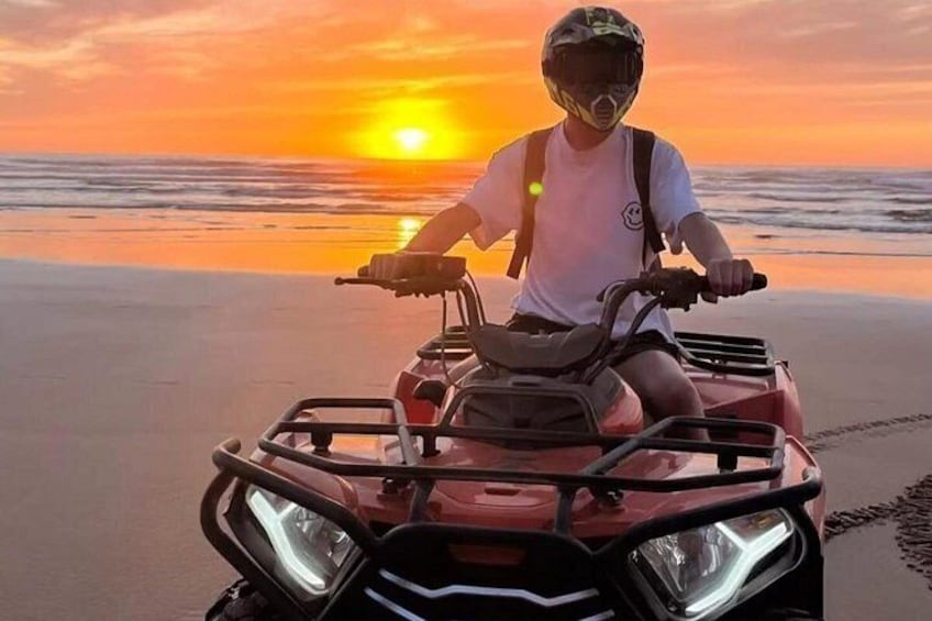 Eine Person fährt bei Sonnenuntergang mit einem Geländefahrzeug am Strand. 4