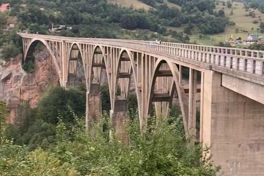 A large concrete bridge with multiple arches spanning a deep gorge. 4