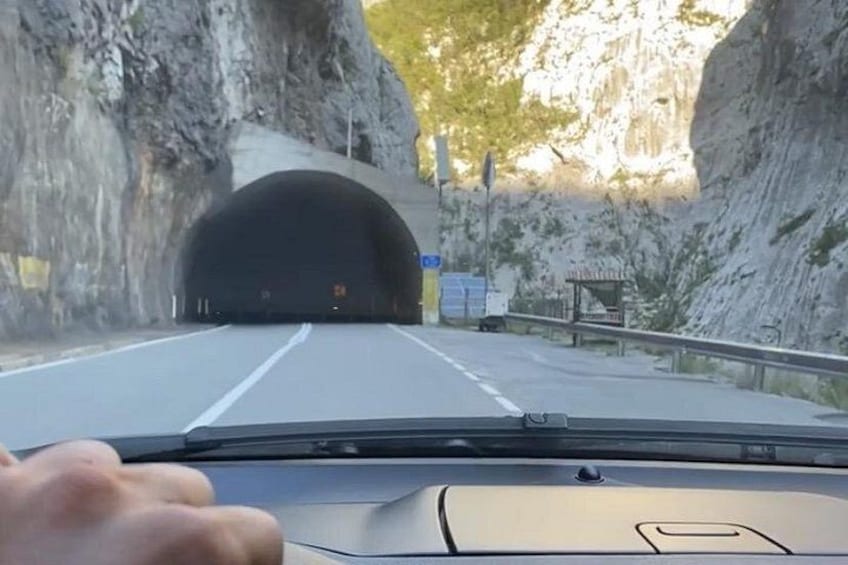 A car driving through a tunnel with rocky cliffs on either side. 5