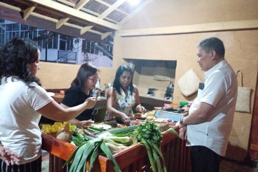 Un groupe de personnes prépare des aliments dans une cuisine, avec des légumes et des ustensiles de cuisine disposés sur le plan de travail. 5