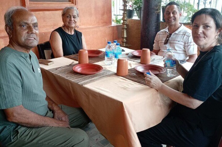 Un groupe de personnes est assis autour d’une table, devant des assiettes, des bouteilles d’eau et une nappe de couleur beige. 4