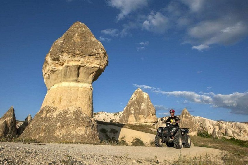 A quad bike on a dirt path with rock formations in the background. 3