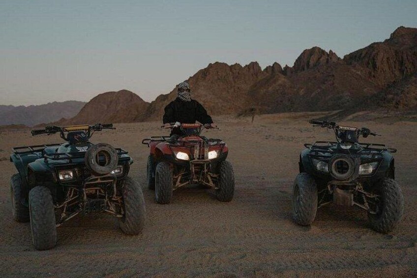 Three ATVs in a desert landscape with rocky terrain. 5