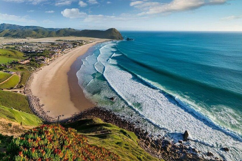 Eine Küstenlandschaft mit Strand, Meereswellen und einer fernen Bergkette. 2