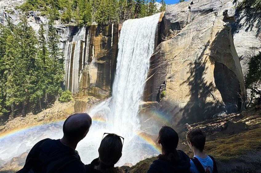 Une cascade surmontée d’un arc-en-ciel, entourée d’arbres et d’un paysage rocheux. 5