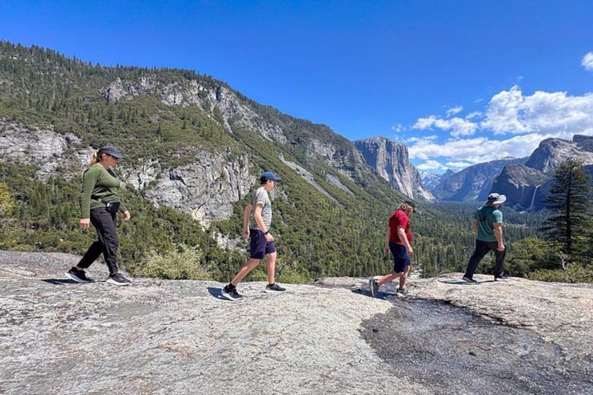 A group of hikers on a rocky trail with mountains in the background. 3