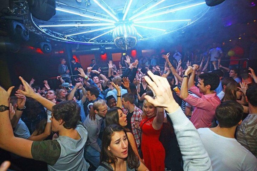 A crowded indoor space with people raising their hands, possibly at a concert or event. 4