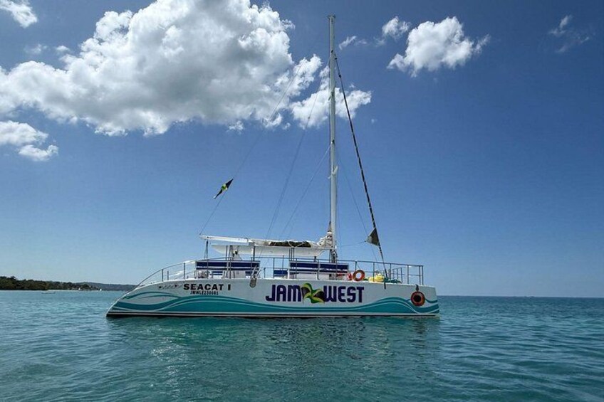 A sailboat named 'JAM WEST' on calm waters with a clear sky. 2