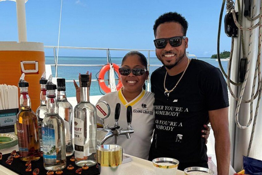 A person standing on a boat with a bottle of liquor and a life preserver in the background. 5