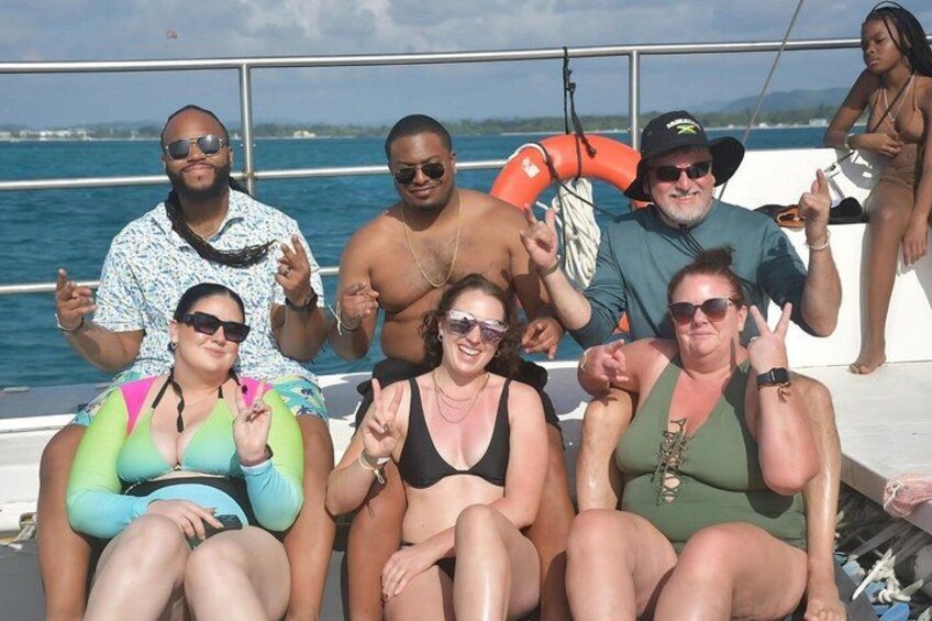 A group of people on a boat with a lifebuoy and a clear blue sky. 3