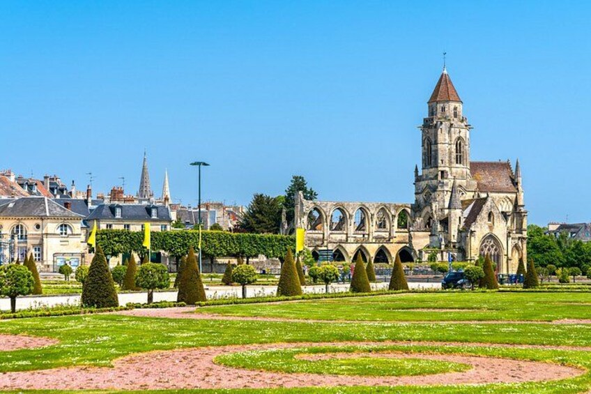 A historic church with a tall tower, surrounded by a well-maintained garden with geometrically shaped hedges. 3