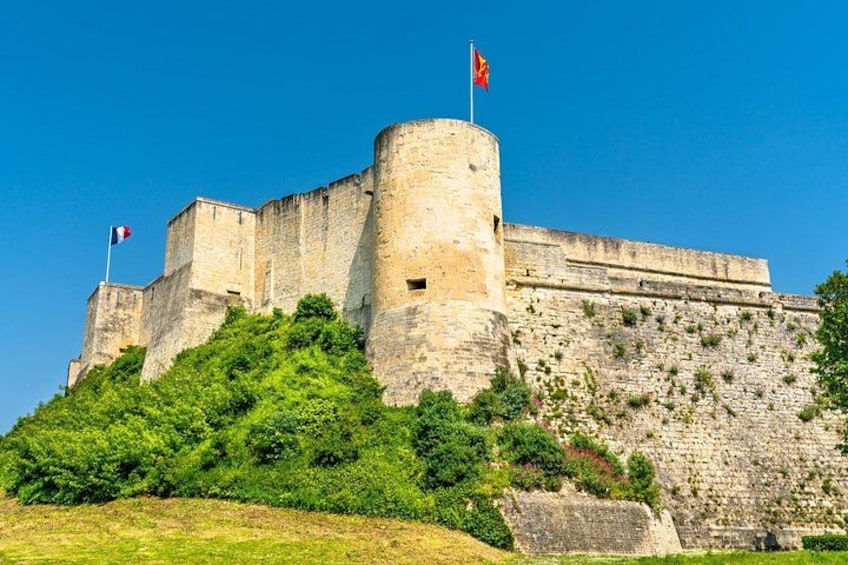 A historic stone castle with a flag, surrounded by lush greenery. 2