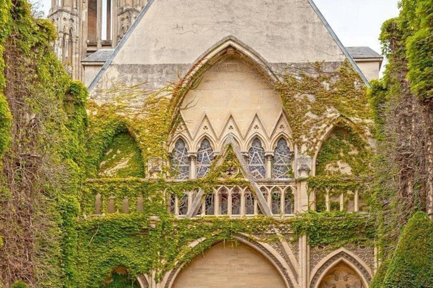 A Gothic-style building with arched windows and a pointed roof, partially covered in ivy. 5
