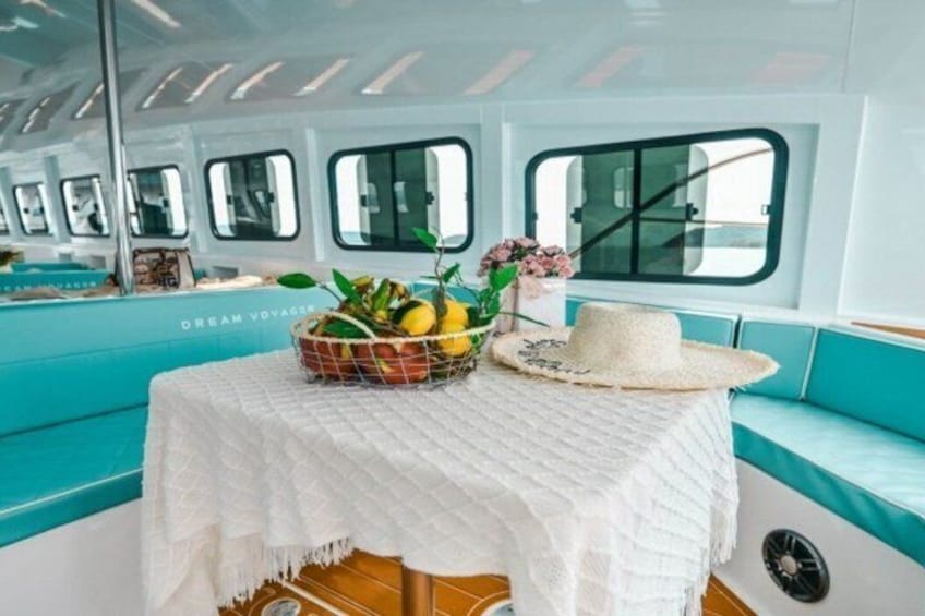 Une table recouverte d’une nappe blanche, un panier de fruits et un chapeau de paille sur un bateau. 5