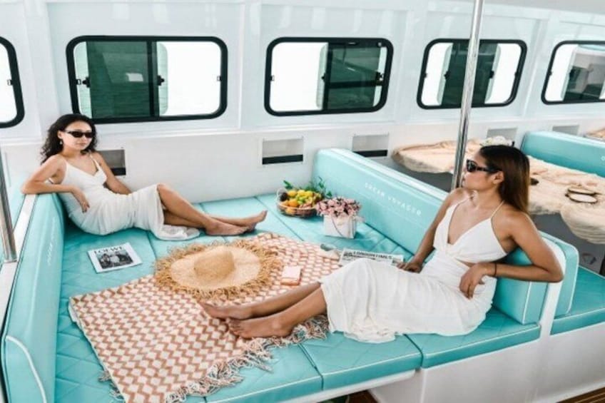 L'intérieur d'un bateau, avec des sièges turquoise, un chapeau de paille et une petite table agrémentée de fleurs. 3