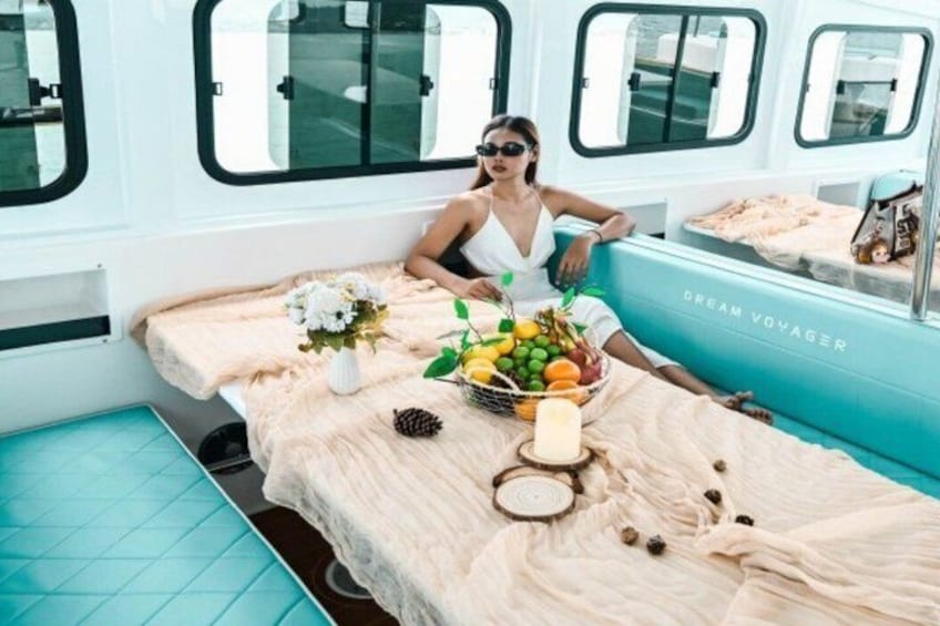Une femme est assise sur un lit, devant une table chargée de fruits et de fleurs. 2