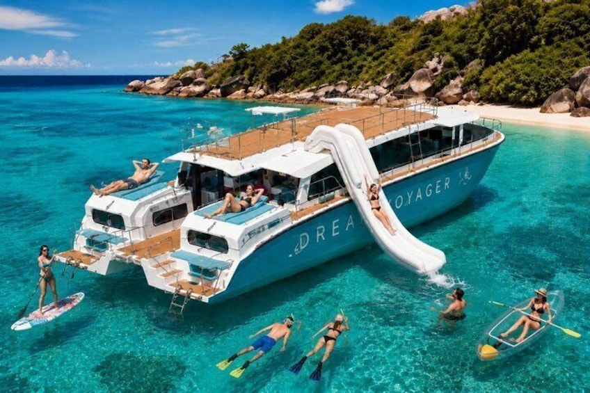 Un yacht doté d’un toboggan, entouré d’une eau turquoise cristalline et d’une côte rocheuse. 1