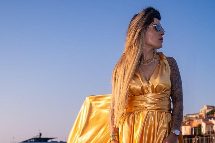 A person in a golden dress standing outdoors with buildings in the background. 2