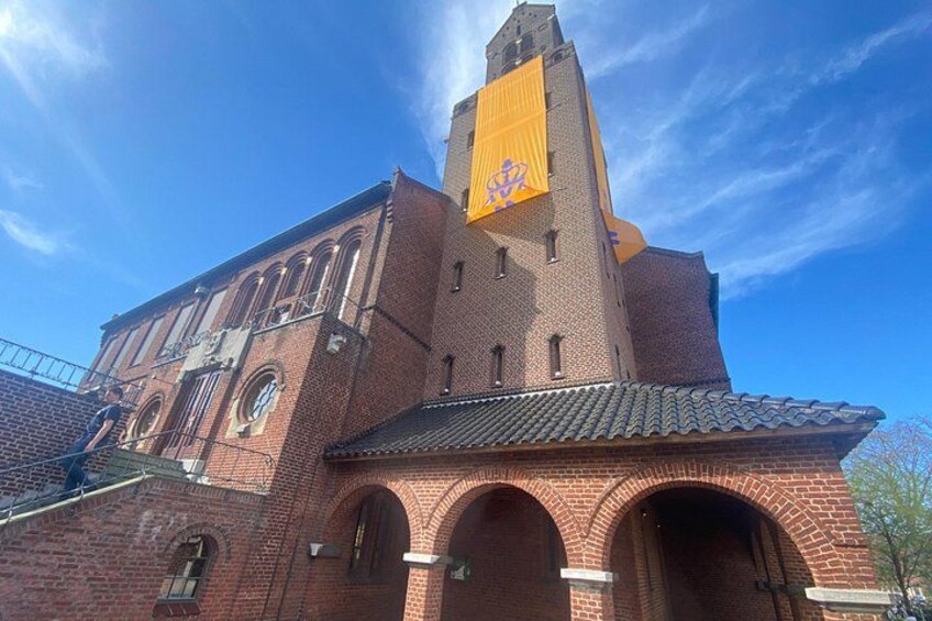 A red brick church with a tall tower and a yellow banner. 1