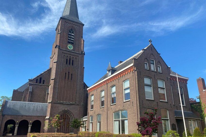 A church with a tall steeple and a brick building with a gabled roof. 2