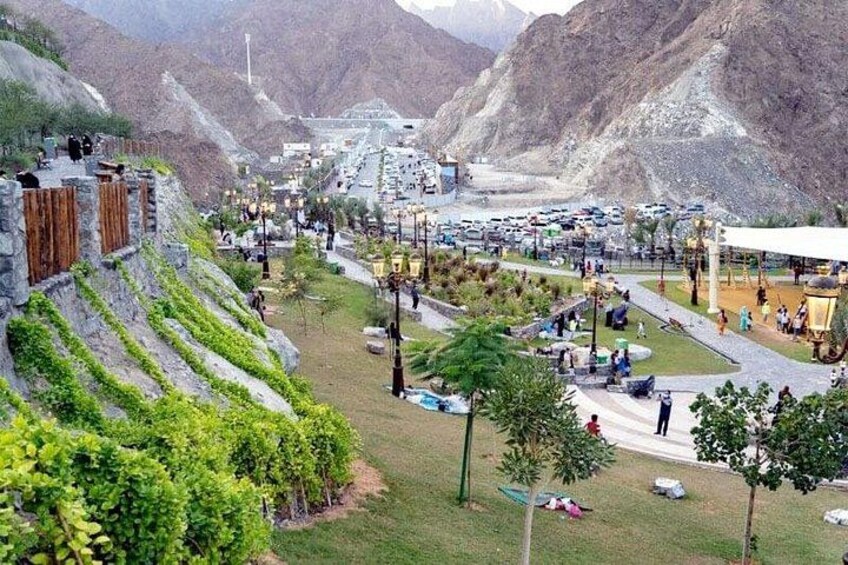 Un paisaje montañoso con un parque, senderos y un edificio grande al fondo. 1