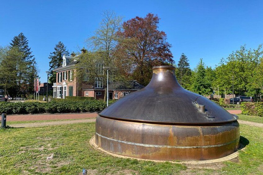 A large metallic sculpture in a park with a building in the background. 2