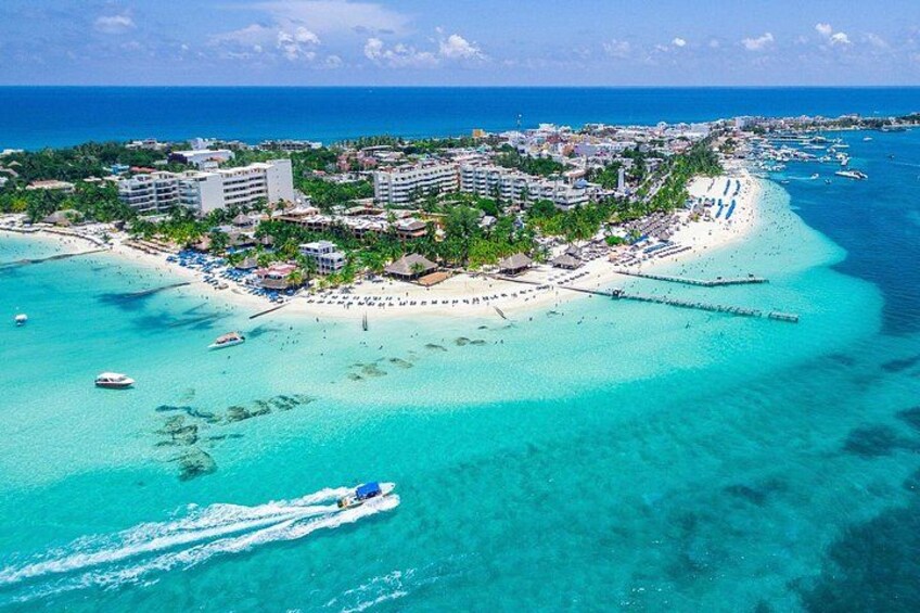 A coastal resort with clear turquoise waters, a pier, and a small island with buildings and a beach. 2