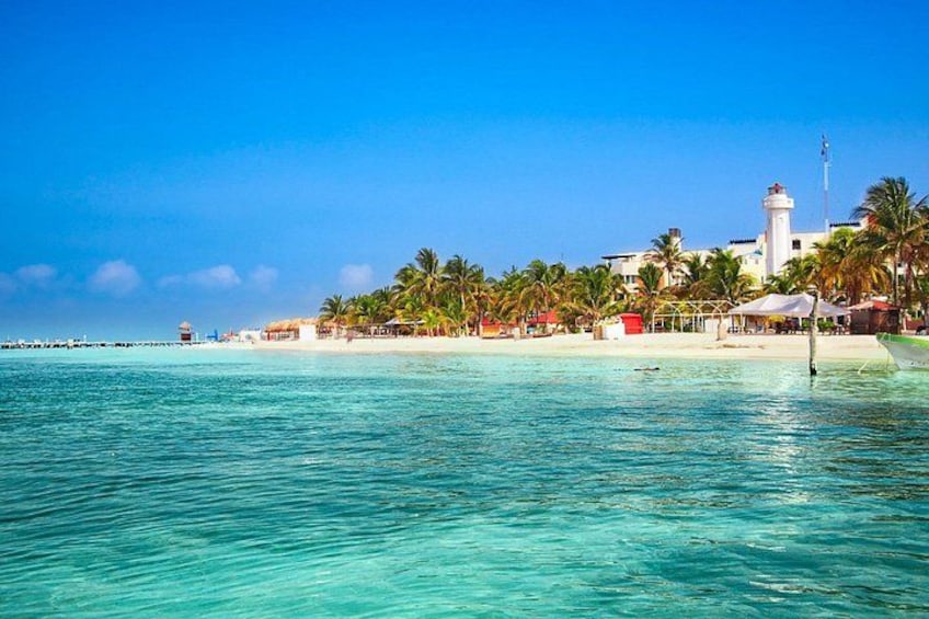 A beach with clear turquoise water, palm trees, a lighthouse, and a pier. 5